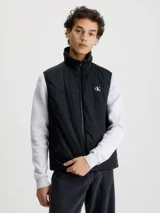 Chaleco negro acolchado de nailon reciclado con cuello alto, cierre de cremallera, bolsillos con cremallera en la cintura y logo de Calvin Klein en el pecho y la nuca.