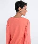 Blusa color salmón con escote redondo, mangas 3/4 amplias y ajuste frontal. Confeccionada en tejido laise.