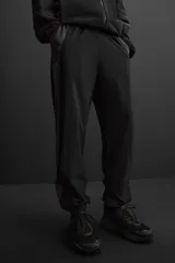 Pantalón relaxed fit confeccionado en tejido técnico ligero y elástico en todas direcciones. Cintura elástica ajustable con cordón interior, bolsillos delanteros y bajo acabado en elástico y ajustable con cremallera.