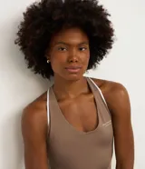 Enterito deportivo corto color marrón topo, ajustado al cuerpo, con escote en V pronunciado y breteles finos blancos que se cruzan en la espalda.