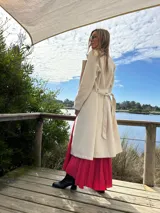 Abrigo trench color crudo, de paño fino con dibujo en sarga, forrado, con cuello solapa, doble botonadura y cinturón con lazada.