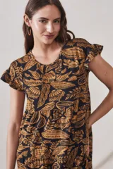 Vestido midi de viscosa con estampado floral en tonos ocre sobre fondo negro. Tiene corte evasé, mangas cortas con volados y largo hasta la rodilla.