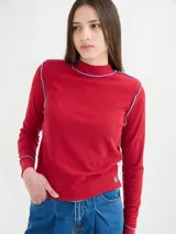 Polera negra de tela rib con cuello alto y mangas largas. Presenta pespuntes rojos en cuello, hombros y puños.