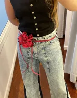 Accesorio de cuero rojo con forma de flor, que puede usarse como colgante, faja o gargantilla.