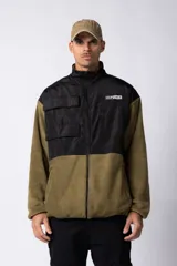 Campera deportiva con cierre frontal, confeccionada en micro polar color verde oliva con recortes en tejido tipo sire color negro en la parte superior. Tiene cuello alto, bolsillos con cierre y logo estampado en el pecho y la espalda.