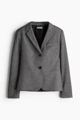 Blazer gris jaspeado de corte entallado, con solapas de muesca, cierre de dos botones, bolsillo superior insertado y bolsillos delanteros con solapa. Tiene hombreras, botonadura frontal, botón decorativo en los puños y abertura atrás.