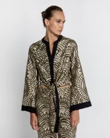 Camisa con estampado geométrico dorado y negro, cuello mao y mangas anchas.