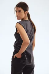 Chaleco gris oscuro con finas rayas verticales blancas, cuello redondo y sin mangas. Incluye cinturón de la misma tela para atar en la cintura.