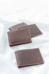 Billetera de cuero pull up engrasado color chocolate, con logo grabado en la esquina inferior derecha. Diseño plegable con múltiples compartimentos para tarjetas y billetes.