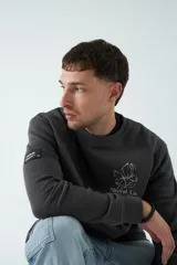 Buzo marrón de felpa con cuello redondo, puños y cintura acanalados. Estampa pequeña en el frente y grande en la espalda con diseño floral y texto.