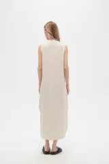 Vestido largo color crema con rayas verticales finas en negro, escote en V con ribete negro y corte holgado.