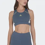 Top deportivo Le Coq Sportif color azul grisáceo con detalles en amarillo pálido y blanco. Presenta un diseño de espalda tipo nadador con tul elástico y costuras en contraste. Logo de la marca en amarillo en el pecho.