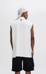 Camisa blanca sin mangas de calce oversize con doble bolsillo y detalle de remaches en el frente, confeccionada en tejido twill de alta calidad.