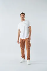 Pantalón cargo color marrón, corte slim, con cierre y botón en la cintura, pasacintos y bolsillos cargo con botones.
