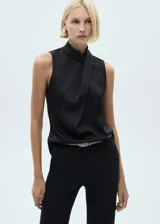 Blusa color crema de tejido fluido satinado, con cuello alto y diseño drapeado.