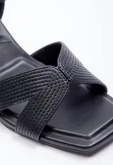 Sandalia alta de símil cuero negra, con taco de 7.5 cm y hebilla en el tobillo, diseño con calados y pespuntes.
