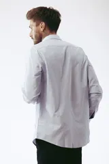 Camisa celeste a rayas verticales blancas, de corte clásico, manga larga y cuello abotonado.