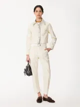 Pantalón color crema de corte slouchy con pinzas en las rodillas y bordados de hongos y chiles con strass.