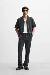 Pantalón negro de corte recto, confeccionado en tejido de mezcla de algodón y lino. Presenta cintura elástica, bolsillos laterales y traseros.