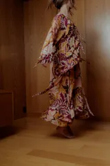Maxi vestido con estampado floral en tonos naranja, rosa y borgoña. Tiene escote off-shoulder elastizado y mangas cortas con volados.
