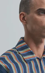 Camisa de manga corta con cuello cubano y estampado a rayas verticales en tonos azul, amarillo y rojo.