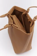 Bolso tipo tote color marrón claro, con textura símil cuero y doble asa de mano con detalle de nudo. Incluye un sobre con cierre.