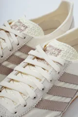 Championes Adidas SL 72 OG, color blanco hueso con detalles en gris topo, confeccionados en nylon y gamuza, con las tres tiras laterales en cuero sintético y suela de goma marrón.
