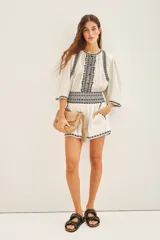 Minifalda blanca de algodón con bordados geométricos negros en el ruedo y cintura.