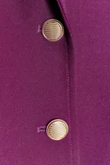 Blazer negra entallada con cuello solapa, manga larga con hombreras, bolsillos delanteros con solapa y cierre frontal con botones dorados.
