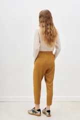 Pantalón de tiro medio color mostaza, de calce holgado que se ajusta al tobillo. Tiene cintura elastizada con tiras regulables.