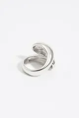 Anillo plateado de metal con diseño en espiral y logo grabado.