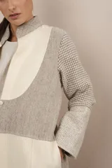 Camisa larga color beige con cuello mao, manga larga con tajo y botón. Diseño con bloques de tela con textura.