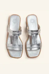 Sandalias bajas de cuero color marrón con costuras blancas a la vista.