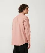 Camisa manga larga color rosa con capucha gris, cierre con botones, bolsillos frontales y corte recto.