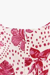 Vestido midi con estampado floral en tonos rosados, de escote recto y tirantes anchos con abalorios. Presenta aberturas laterales en la cintura y cierre trasero con cremallera oculta.