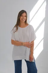 Blusa blanca de lino con cuello redondo, mangas cortas, bolsillo en el pecho y detalle de bordado calado en el lateral inferior. Corte holgado.