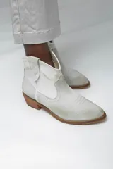 Botines de cuero color gris claro, estilo texano, con puntera fina, caña baja y taco de madera.