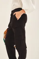 Pantalón cargo negro de corte holgado, con cierre y botones frontales, elástico en la cintura y en los ruedos. Cuenta con bolsillos laterales y en las piernas.