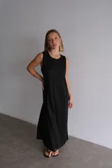 Vestido largo azul marino de tejido acanalado, con escote redondo y mangas cortas tipo hombrera. Presenta una abertura lateral en la falda.