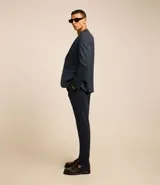 Pantalón de traje de corte super slim, color azul oscuro, confeccionado en tejido de poliviscosa con textura discreta. Presenta trabillas en la cintura, cierre de cremallera y botón, y bolsillos laterales y traseros.