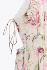 Vestido largo con estampado floral, cuello redondo y tirantes finos. Presenta elástico en la cintura con aberturas y lazadas laterales, volantes en el mismo tejido, forro interior a contraste y abertura frontal en el bajo. Cierre en la espalda con botón.
