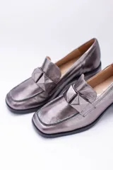 Mocasines de cuero color peltre con taco cuadrado y aplique geométrico al tono.