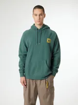 Buzo hoodie azul marino con capucha y cordones ajustables, de corte holgado y puños elásticos. Presenta un estampado en la espalda con una cruz dorada dentro de un cuadrado y texto en japonés.