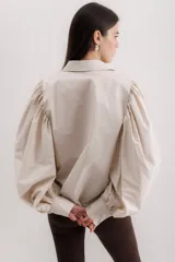 Camisa color beige de algodón con mangas abullonadas y cierre con botones.