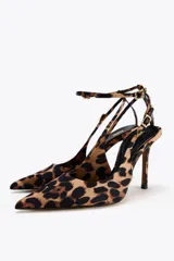 Zapato destalonado de tacón alto con estampado animal, acabado en punta y cierre mediante hebilla en la pulsera al tobillo.
