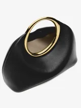 Bolso mini tipo clutch color negro, de cuero napa, con forma orgánica y asa de aro dorada integrada.