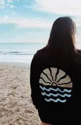 Buzo negro con estampa de sol naciente y olas en la espalda.
