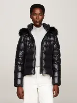 Campera puffer negra de nailon con relleno de plumón, capucha fija con ribete extraíble de pelo sintético, cuello alto, cierre de cremallera, bolsillos laterales con cremallera y parche con el logo de Tommy Hilfiger en la manga.