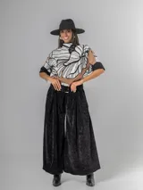 Pantalón ancho de corderoy negro con pliegues marcados en la parte delantera y cintura elástica. Incluye un cinturón negro con hebilla cuadrada.