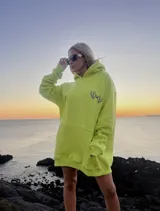Hoodie oversize color verde neón con capucha, bolsillo canguro y puños ajustados. Estampado pequeño en el pecho con logo de la marca.